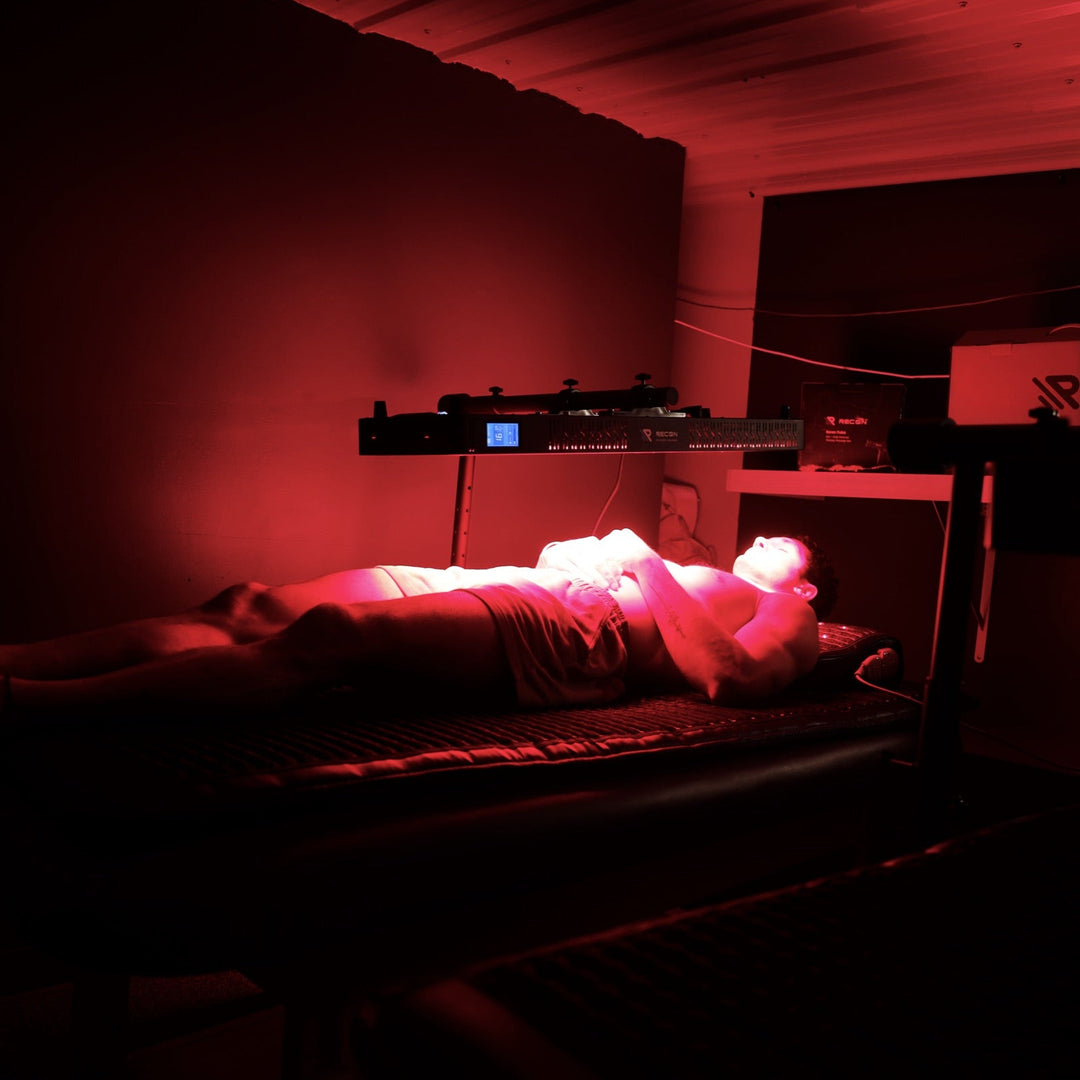 Person lying on a bed with red lighting in a room.