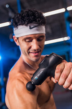 Athlete working his forearm with the RECON Pulse Massage Gun in a gym