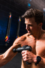 Athlete using the RECON Pulse Massage Gun on his shoulder in a gym